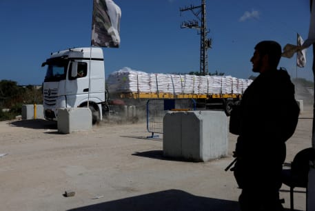  An Israeli soldier stands guard as a truck carrying humanitarian aid makes its way to the Gaza Strip at Erez Crossing in southern Israel, May 5, 2024.