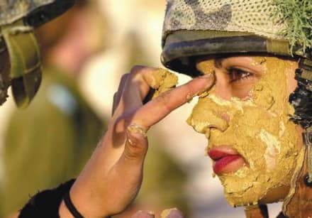 A female IDF soldier paints a comrade with mud.