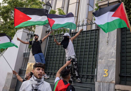 Demonstrators wave Palestinian flags at the entrance of the Egyptian embassy, in Athens, Greece