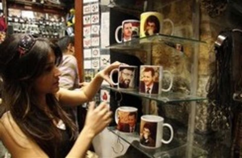 A Syrian woman looks at mugs imprinted with pictur (photo credit: AP)