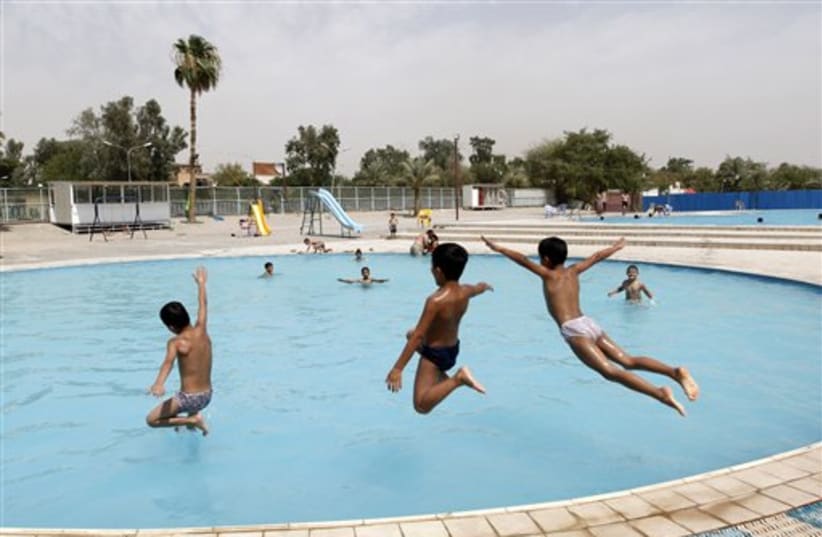 Boys leap into a public swimming pool in Baghdad, Iraq, Wedn (photo credit: AP)