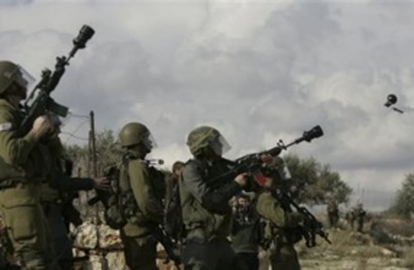 IDF soldiers firing stun grenades in Bil'in 311 (photo credit: AP)