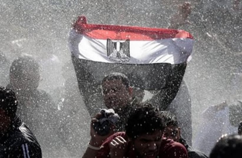 Egyptian protester with flag, water cannon - Gallery (photo credit: AP)
