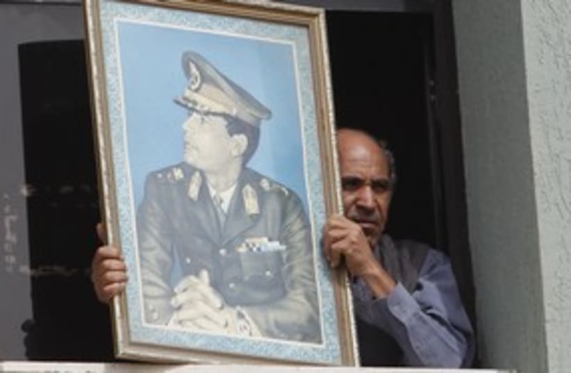 man holds pic of Gaddafi_311 (photo credit: Chris Helgren / Reuters)