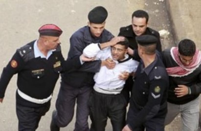 Injured protester escorted by Jordanian security 311 (R) (photo credit: REUTERS/Muhammad Hamed )