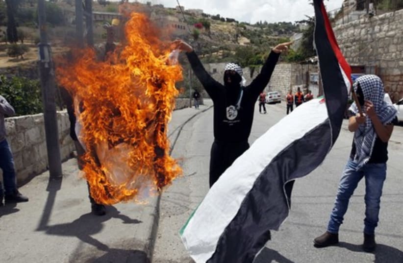 Palestinians burning a flag during Silwan clashes GALLERY (photo credit: REUTERS/Nir Elias)