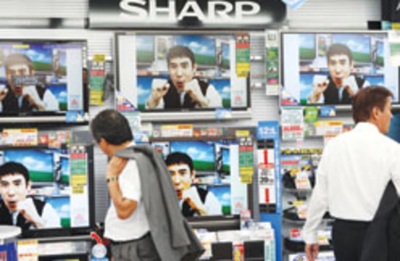 A shopper looks at Sharp flat-panel TVs at an electronics shop in Tokyo. Japan's return to growth in the second quarter marked the end of a yearlong recession. (photo credit: AP)