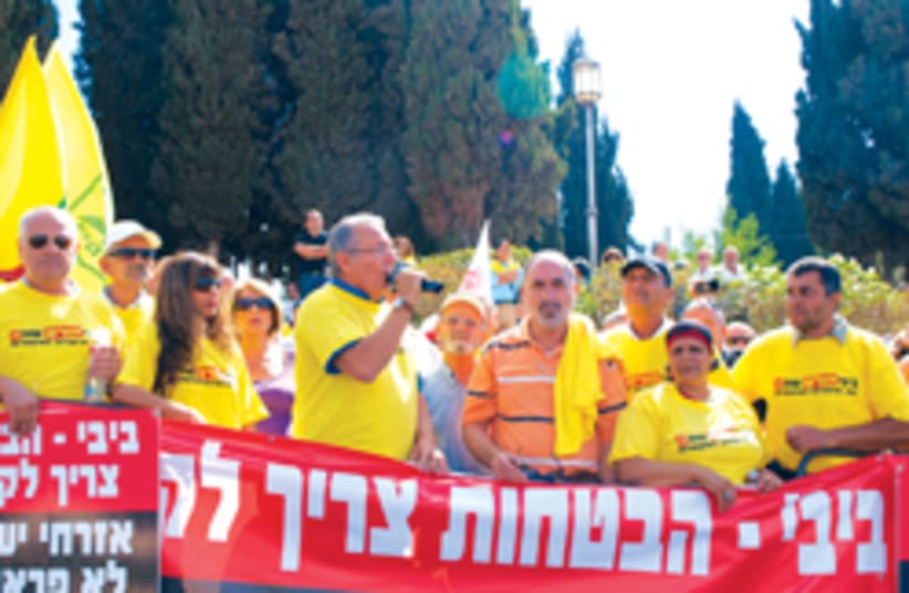 ULA chairman Shlomo Buhbut provokes the jeering crowd during a protest against municipal budget cuts outside the PMO, Monday. (photo credit: ABE SELIG)