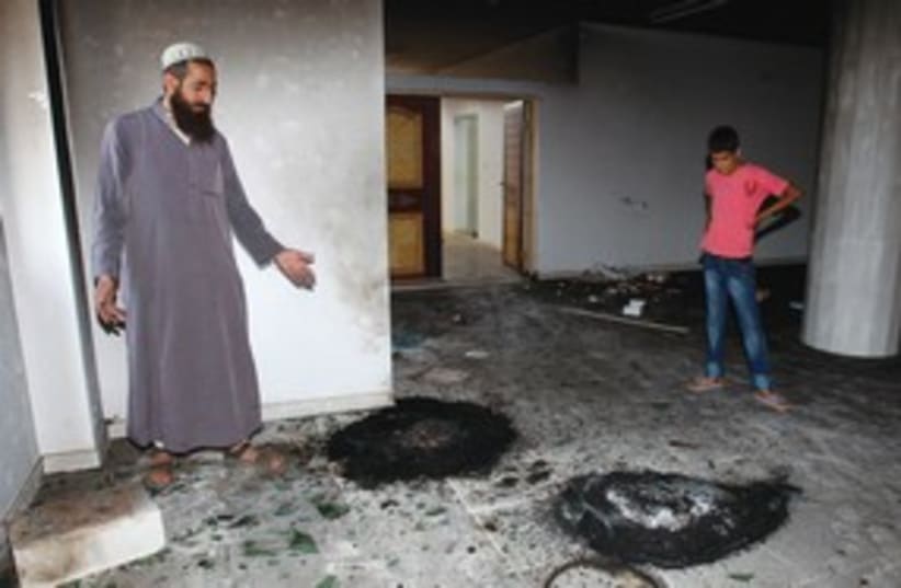 Palestinians look at burned tires in mosque 311 (photo credit: Reuters)