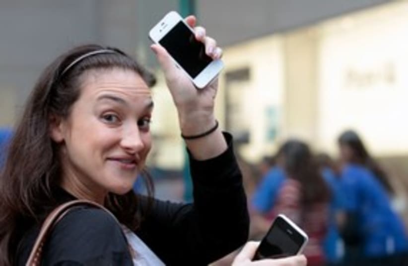 A woman showing off her new iPhone 4s in NY 311 (R) (photo credit: REUTERS/Brendan McDermid)