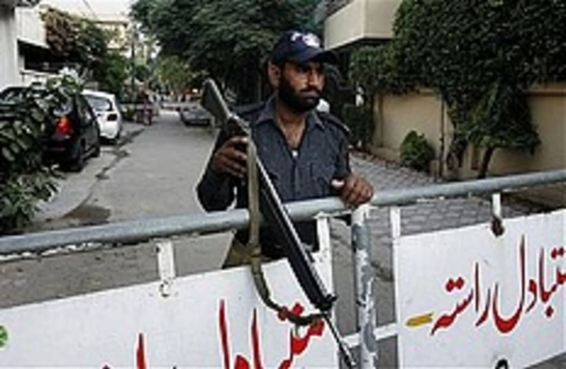 A Pakistani police officer stands guard behind a barricaded street leading to the house of Hafiz Muhammad Saeed, Monday (photo credit: AP)