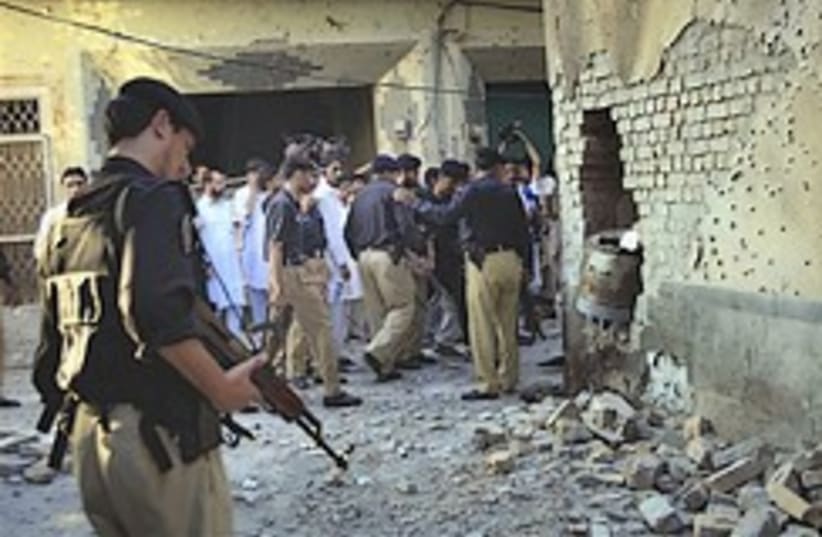 Pakistan police officers examine the site of a suicide bombing on the outskirts of Peshawar on Sunday. (photo credit: AP)