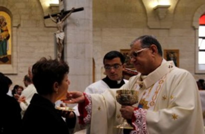 Latin Patriarch Twal gives communion in Bethlehem 311 (R) (photo credit: REUTERS/Ammar Awad)