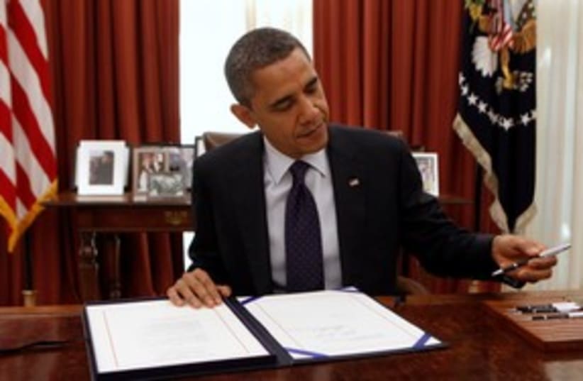 Barack Obama signing a bill 311 (R) (photo credit: REUTERS/Kevin Lamarque)
