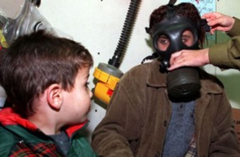 Boy watches as mom is fitted for a gas mask 311 (R) (photo credit: Jim Hollander / Reuters)