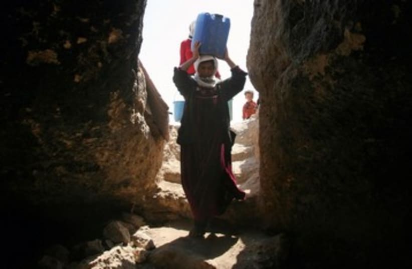 Palestinian woman carrying water 390 (R) (photo credit: Nayef Haslamoun / Reuters)