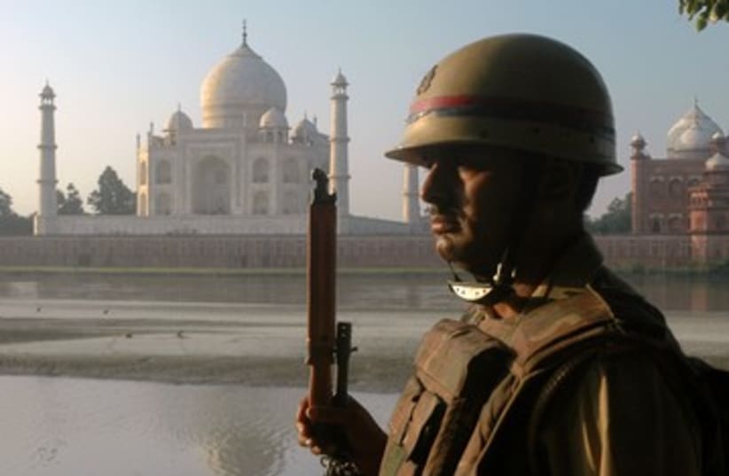 An Indian police officer standing guard 390 (R) (photo credit: Stringer India / Reuters)