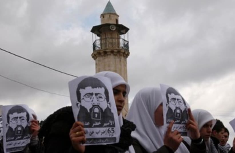 Palestinian students hold signs depicting Khader Adnan 390 R (photo credit: REUTERS/Abed Omar Qusini)