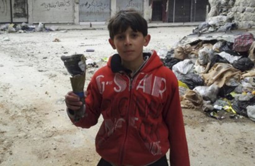 Boys hold remains of mortar in Homs neighorhood R 390 (photo credit: REUTERS)