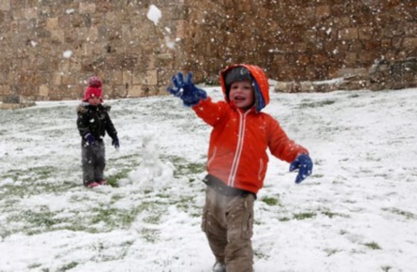 One kid hurls a snowball as the other guards the snowman (photo credit: Marc Israel Sellem)