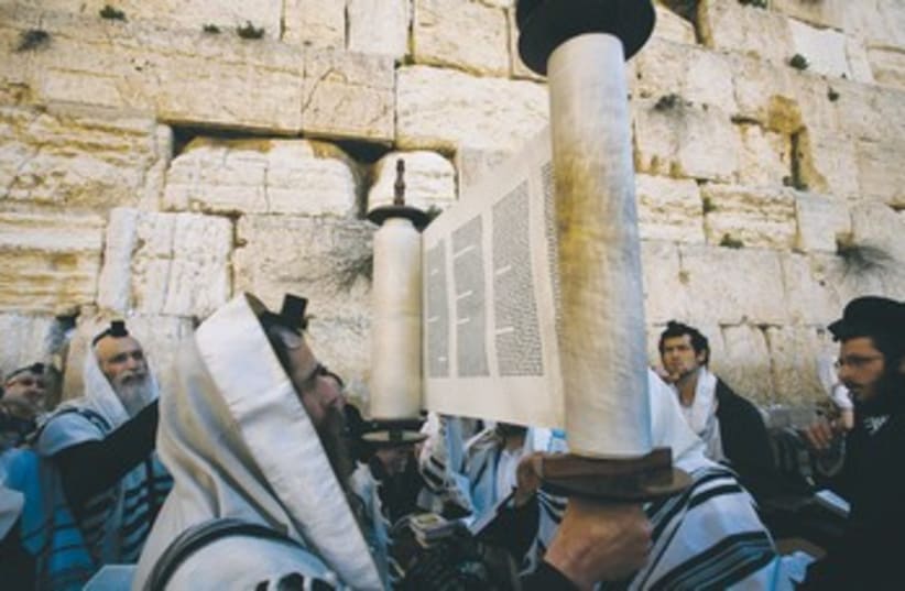 A worshiper holds up a Torah scroll 370 (photo credit: Reuters)