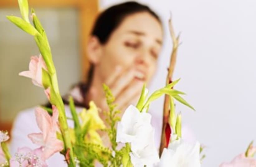 Young woman sneezing in front of a bouquet of flowers 370 (photo credit: Thinkstock/Imagebank)