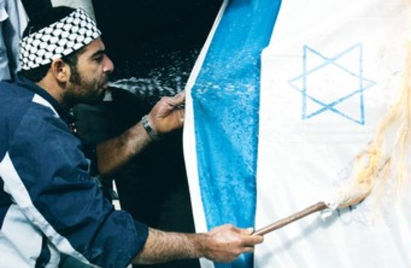 Palestinian man spits gasoline on Israeli flag 370 (R) (photo credit: Reuters)