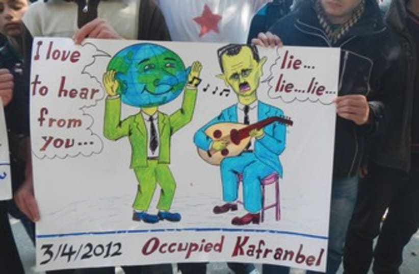 Demonstrators hold sign at protest in Kafranbel, near Idlib  (photo credit: reuters)