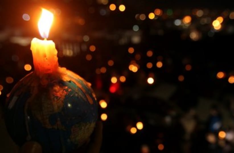 People hold candles during Earth Hour (photo credit: REUTERS/Ali Jarekji)