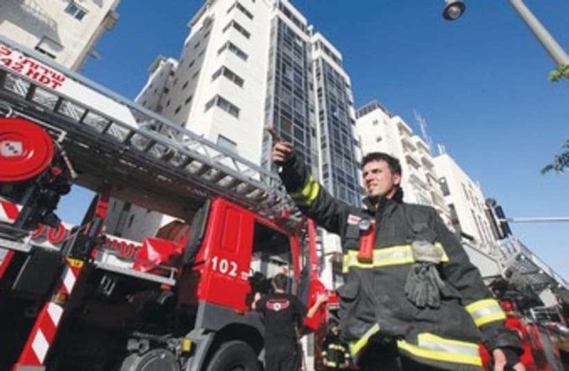 FIREFIGHTER stands outside an apartment building fire (photo credit: Marc Israel Sellem/The Jerusalem Post)
