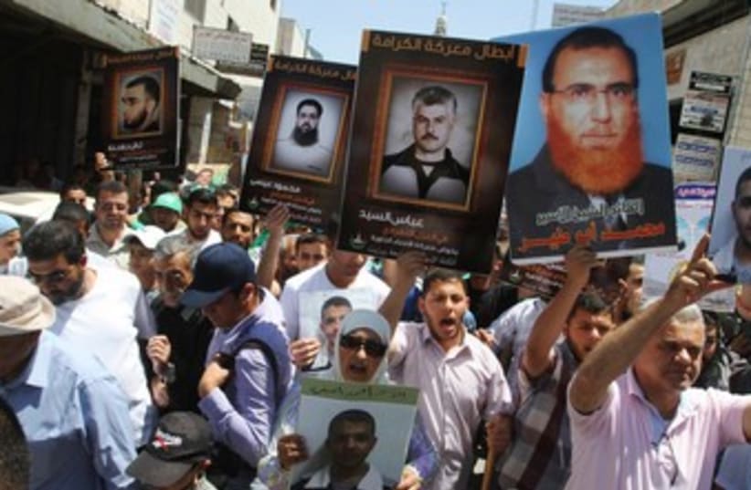 Palestinians in Ramallah hold pictures of prisoners 370 (R) (photo credit: REUTERS/Mohamad Torokman)