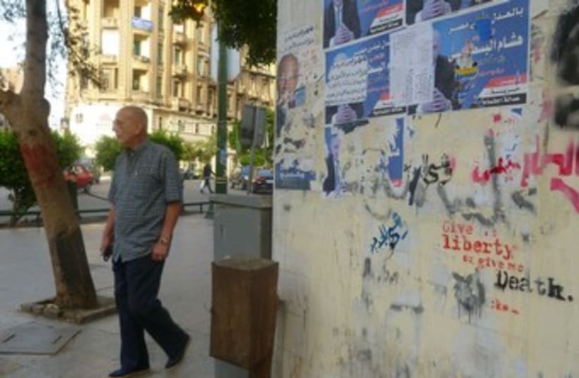 A man walks by a graffitied wall in DT Cairo 370 (photo credit: Eliezer Sherman)