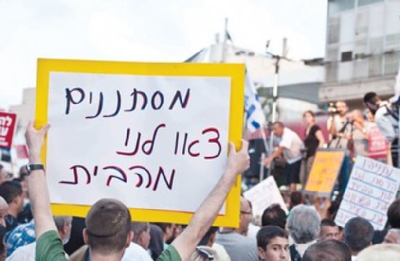 Man holding anti-migrant sign 370 (photo credit: Asaf Kliger/Israel Post)