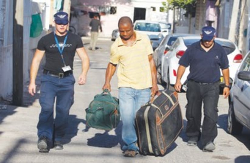 Immigration officers escort African migrant 370 (R) (photo credit: Baz Ratner/Reuters)