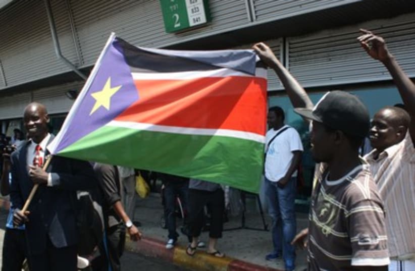 Migrants dance with flag of South Sudan (photo credit: Ben Hartman)