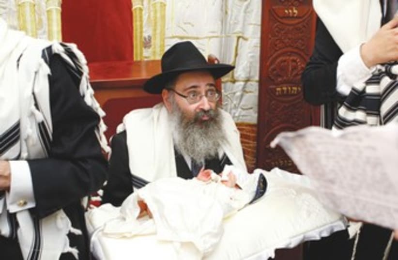 Rabbi holds boy for circumcision (photo credit: REUTERS)