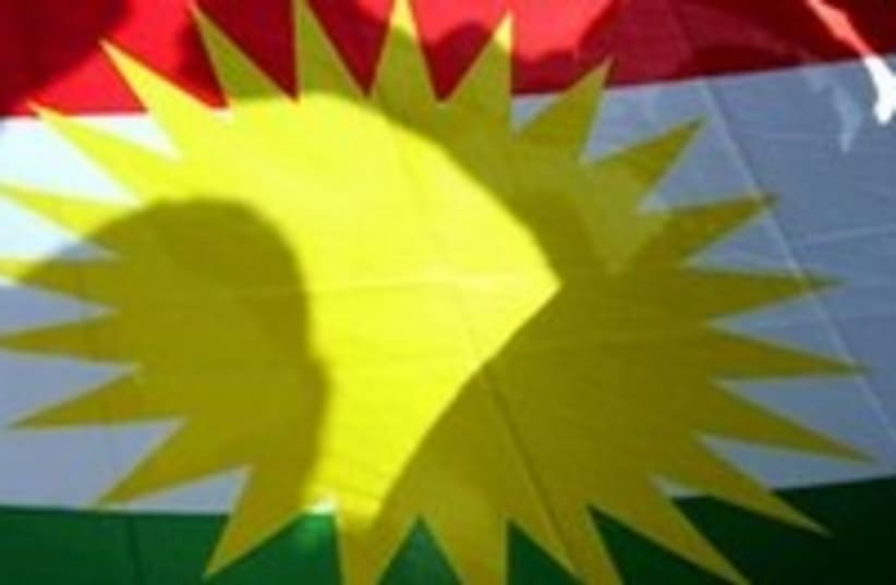 Kurds pose behind Kurdish flag_300 (photo credit: Mike Finn-Kelcey/Reuters)