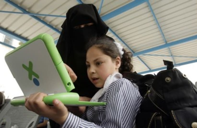 Gaza teacher shows a girl how to use computer 370 (R) (photo credit: Ibraheem Abu Mustafa / Reuters)