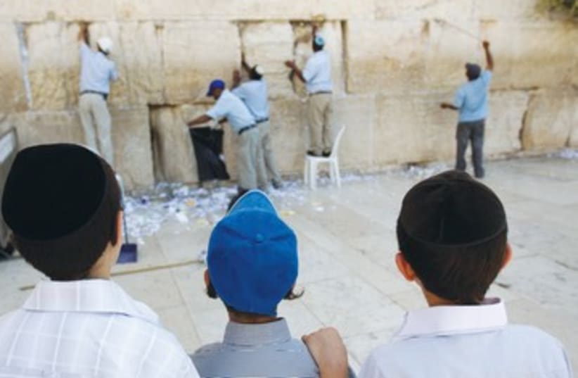 Boys watch notes removed from kotel 390 (photo credit: Ronen Zvulun/Reuters)