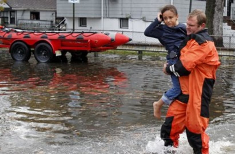 Rescue worker carries girl to safety from flood waters  (photo credit: REUTERS/ Adam Hunger )