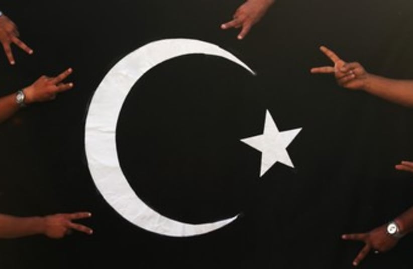 Protesters gesture in front of black flag of Cyrenaica  370 (photo credit: REUTERS/Esam Al-Fetori)