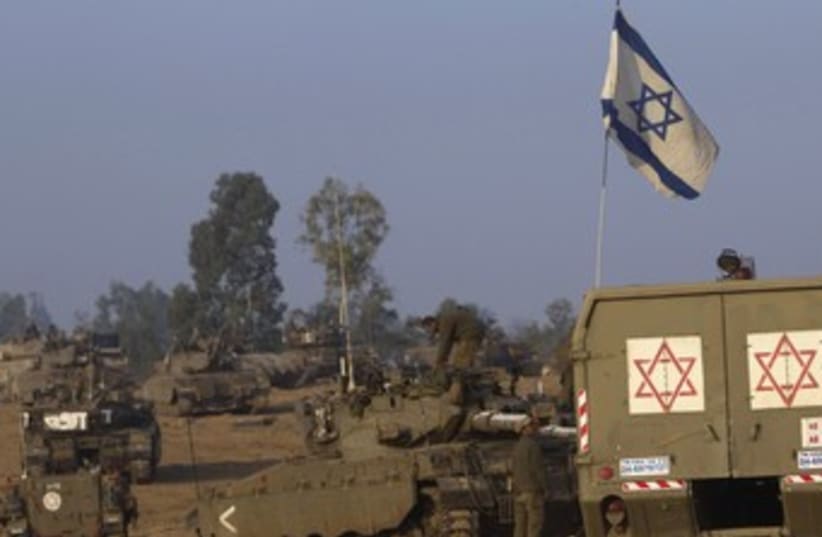 IDF tanks and a flag on the Gaza border 370 (photo credit: Ronen Zvulun / Reuters)