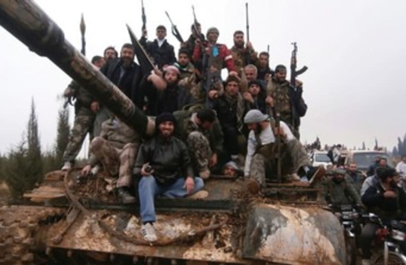 FREE SYRIAN Army fighters pose on a tank 370 (R) (photo credit: Reuters)