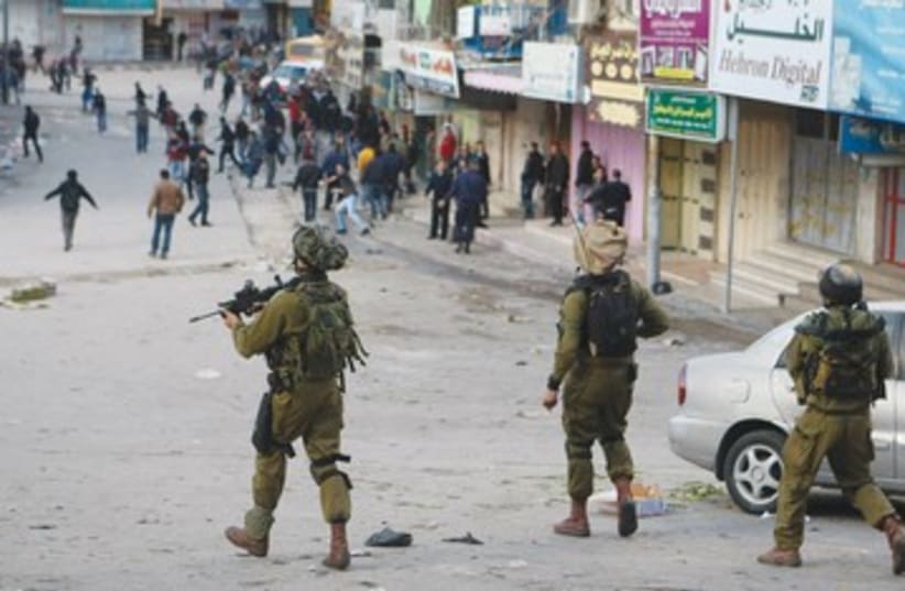 IDF Soldiers disperse Palestinian rioters in Hebron 390 (photo credit: Reuters)