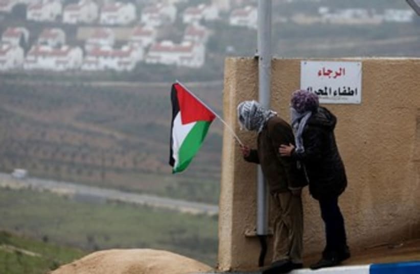 Palestinians hold a flag in the West Bank 370 (photo credit: Reuters/Mohamad Torokman)