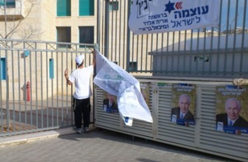 Bayit Yehudi activist removes banner after CEC ruling 370 (photo credit: Yonah Jeremy Bob)