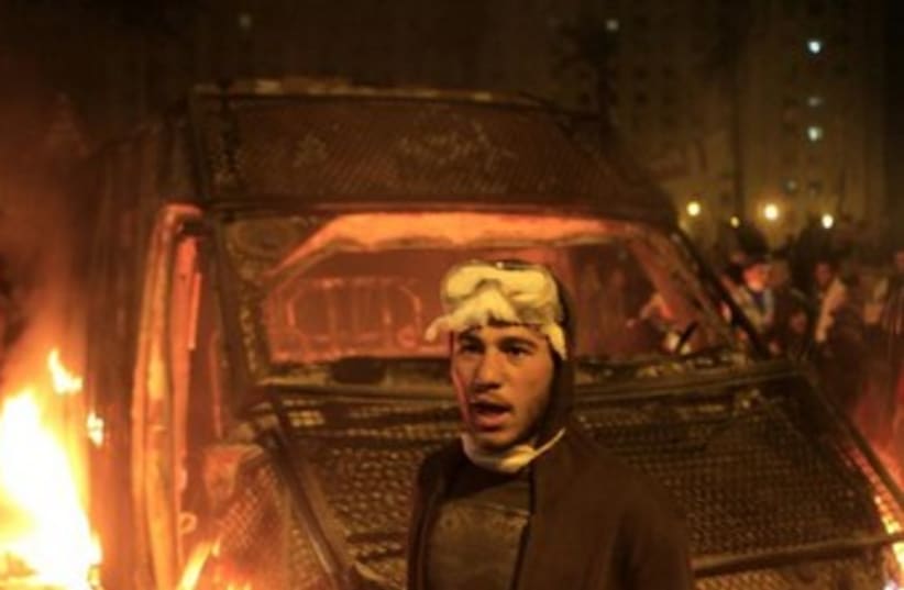 Egyptian protester stands in front of burning riot car 370 (photo credit: reuters)