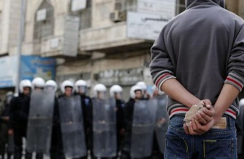 Palestinian protester near Palestinian riot police 370 (photo credit: REUTERS/Darren Whitesid)