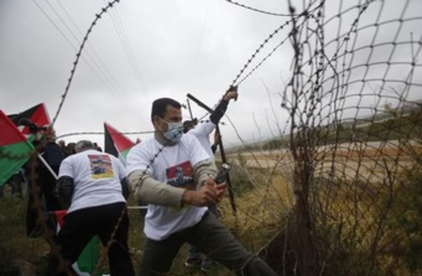 Palestinian activists cut a part of a fence (photo credit: REUTERS/Mohamad Torokman)