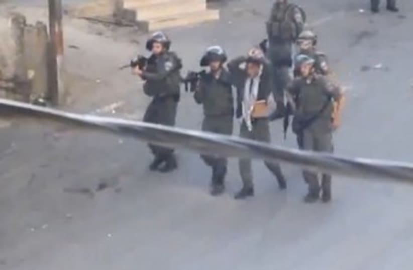 Officers with bound Palestinian teen 370 (photo credit: YouTube Screenshot)